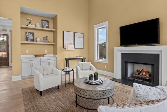 sitting room featuring built in shelves, a wealth of natural light, and light hardwood / wood-style flooring