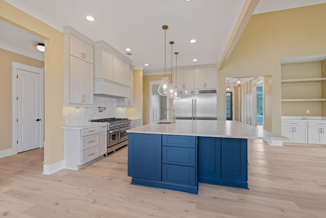 kitchen with high end appliances, sink, decorative light fixtures, a large island, and white cabinetry