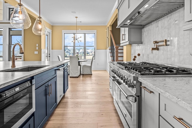 kitchen featuring wall chimney range hood, sink, double oven range, light stone countertops, and decorative light fixtures