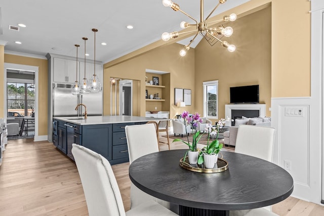 dining room with sink, crown molding, built in features, and light hardwood / wood-style floors