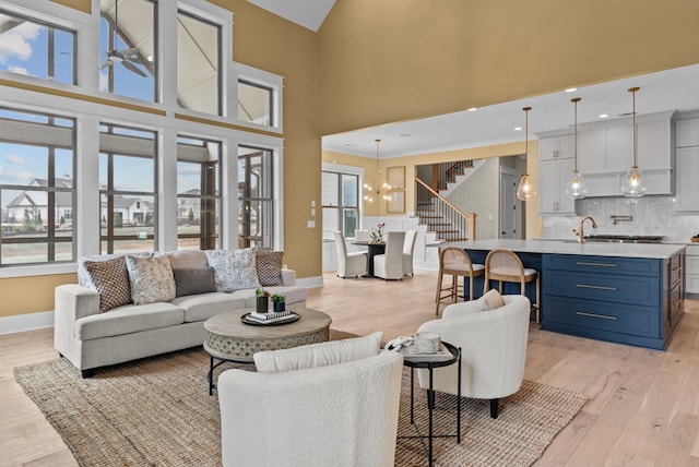 living room featuring a high ceiling, a notable chandelier, and light wood-type flooring