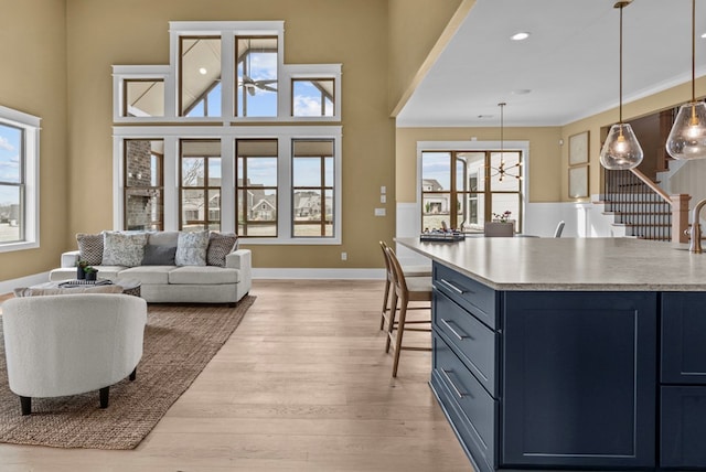 kitchen featuring pendant lighting, ornamental molding, blue cabinets, and light hardwood / wood-style flooring