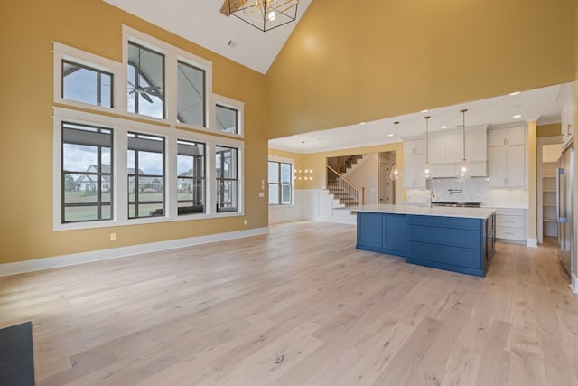 kitchen featuring high vaulted ceiling, white cabinets, blue cabinets, decorative backsplash, and decorative light fixtures