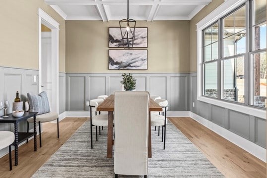 dining space featuring coffered ceiling, beamed ceiling, and light wood-type flooring