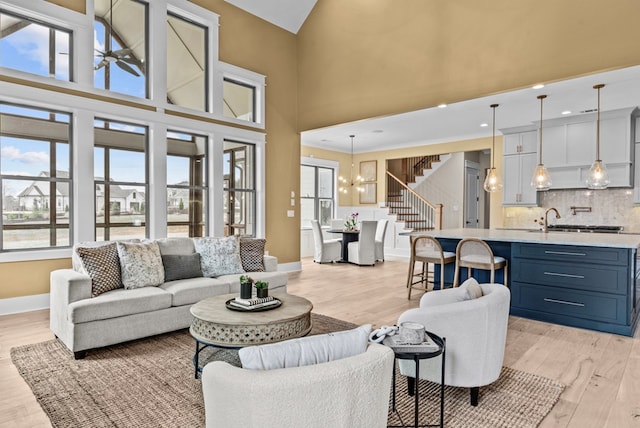 living room with an inviting chandelier, sink, light hardwood / wood-style floors, and a high ceiling