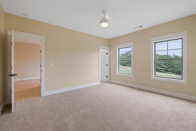 spare room with ceiling fan and light colored carpet