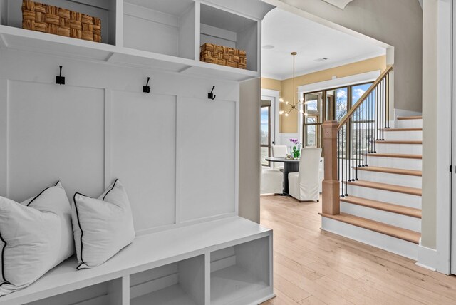 mudroom with hardwood / wood-style flooring, ornamental molding, and a notable chandelier