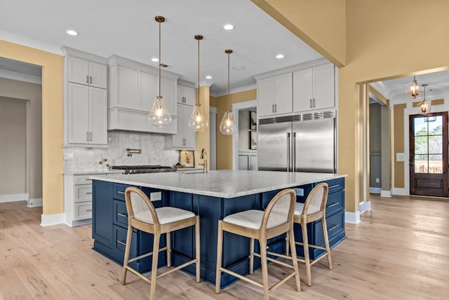 kitchen with a large island, pendant lighting, appliances with stainless steel finishes, white cabinetry, and ornamental molding