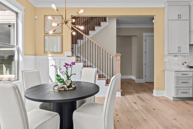 dining area with ornamental molding, a chandelier, and light hardwood / wood-style floors