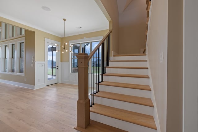 staircase with a chandelier, hardwood / wood-style flooring, and ornamental molding