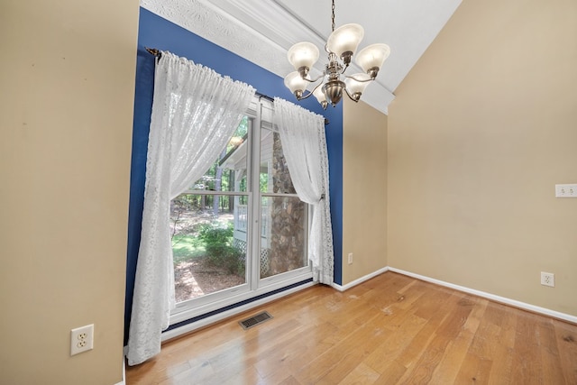 unfurnished dining area featuring baseboards, visible vents, an inviting chandelier, and wood finished floors