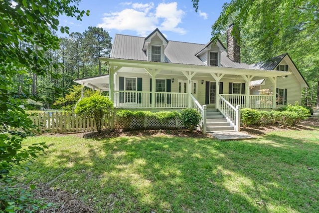 view of front of home featuring a front lawn, covered porch, a chimney, and metal roof