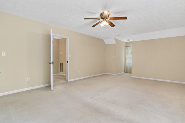 spare room featuring light colored carpet, ceiling fan, visible vents, and baseboards