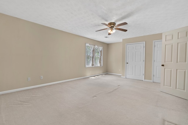 unfurnished bedroom featuring a textured ceiling, baseboards, light colored carpet, and ceiling fan