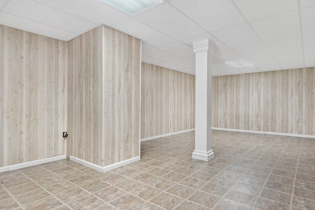 finished below grade area featuring wood walls and a drop ceiling