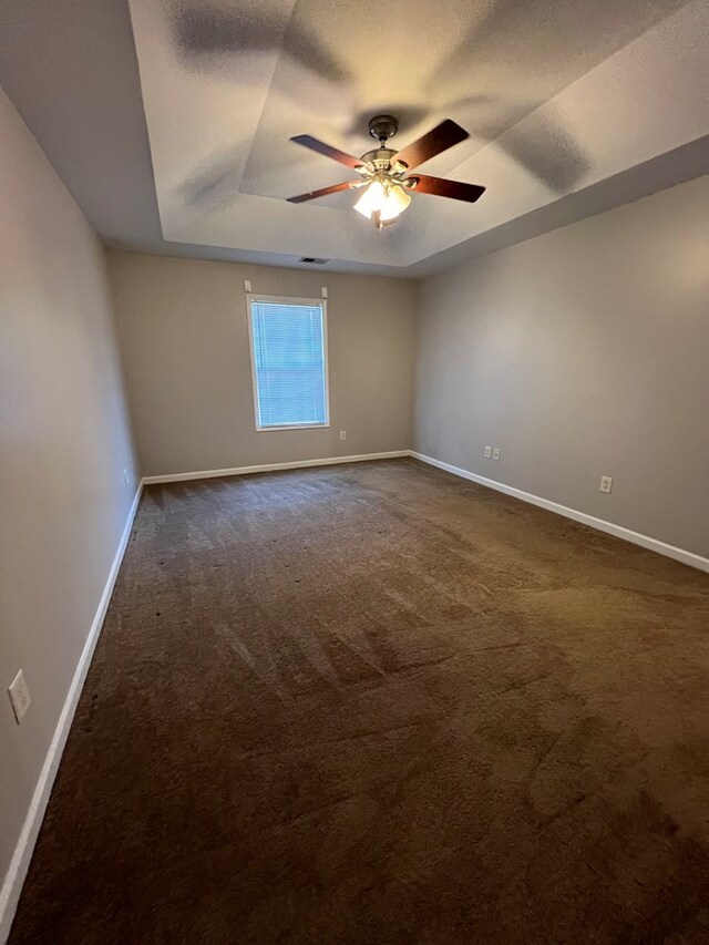 carpeted empty room with ceiling fan and a tray ceiling