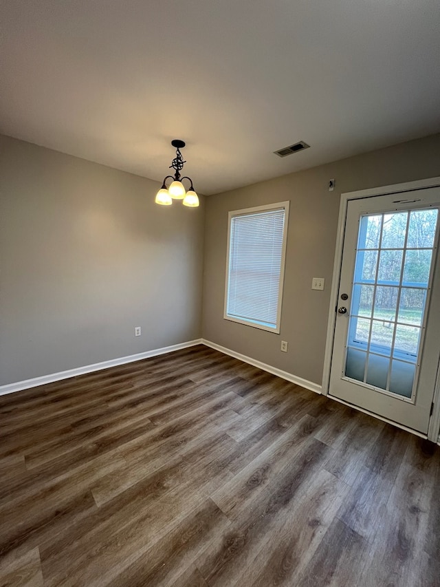 unfurnished dining area with a chandelier and dark hardwood / wood-style floors