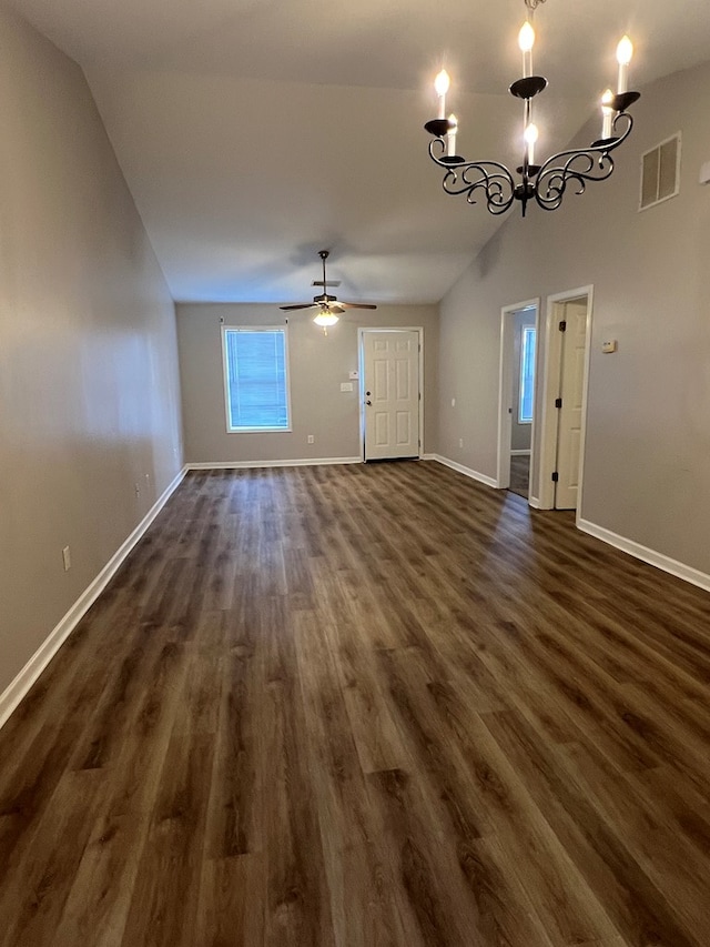 unfurnished living room with ceiling fan with notable chandelier, vaulted ceiling, and dark hardwood / wood-style floors