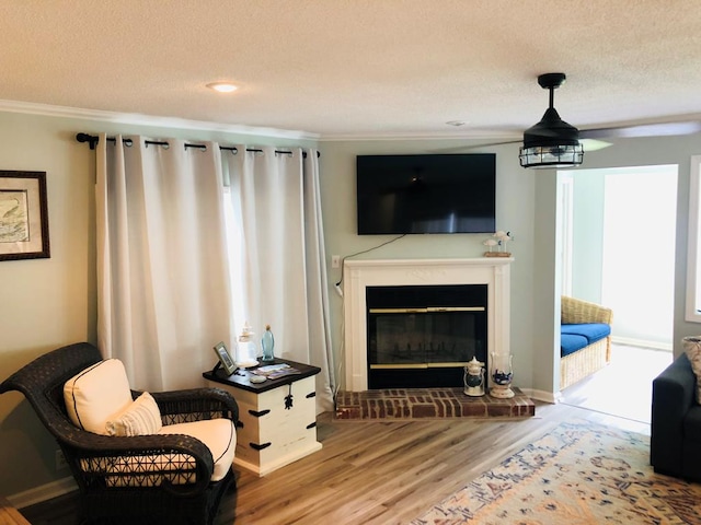 living room featuring a fireplace, a textured ceiling, hardwood / wood-style flooring, and crown molding