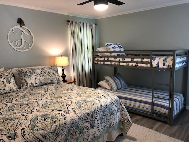 bedroom with dark wood-type flooring, ceiling fan, and ornamental molding