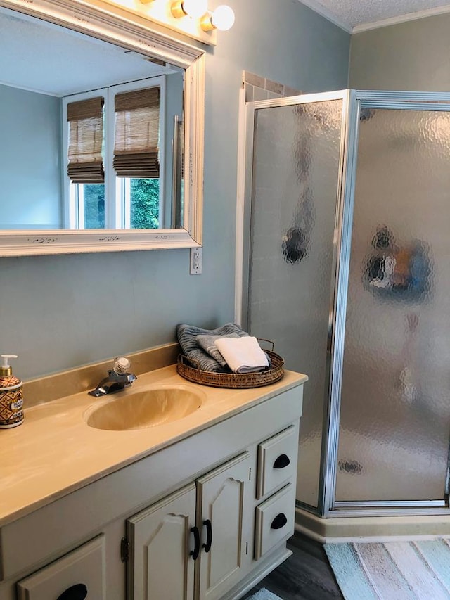 bathroom featuring wood-type flooring, vanity, a textured ceiling, and walk in shower