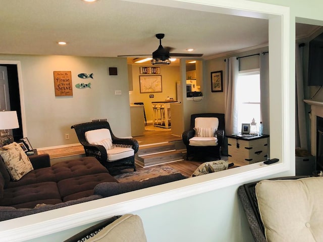 living room with a fireplace, ceiling fan, hardwood / wood-style floors, and crown molding