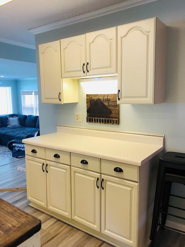 kitchen with white cabinets, crown molding, and light hardwood / wood-style flooring