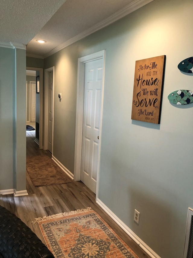 corridor featuring dark hardwood / wood-style floors, ornamental molding, and a textured ceiling