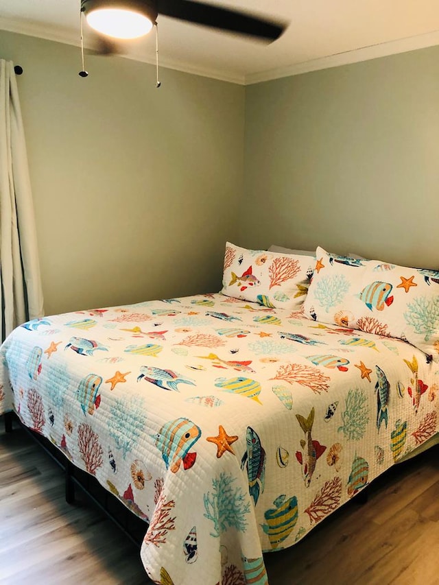 bedroom with hardwood / wood-style floors, ceiling fan, and crown molding