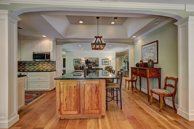 136 Kings Rd, Milledgeville, GA 31061 - kitchen featuring stainless steel microwave, a raised ceiling, light wood finished floors, ornate columns, and ornamental molding