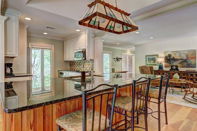 136 Kings Rd, Milledgeville, GA 31061 - kitchen featuring stainless steel microwave, healthy amount of natural light, light wood finished floors, recessed lighting, and white cabinetry