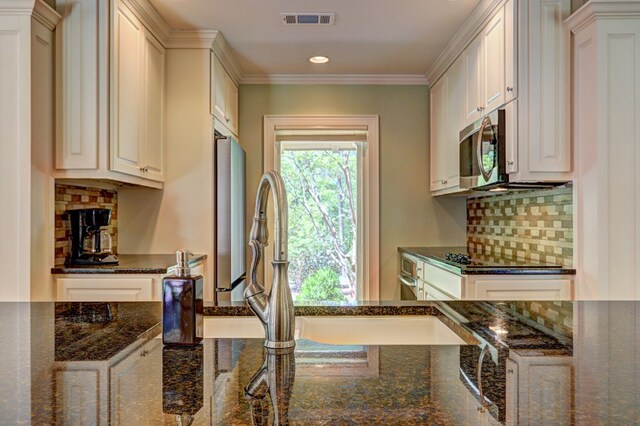 136 Kings Rd, Milledgeville, GA 31061 - kitchen with appliances with stainless steel finishes, dark stone counters, tasteful backsplash, recessed lighting, and ornamental molding