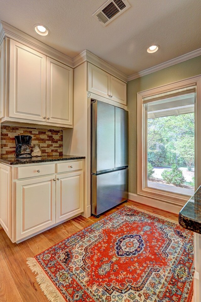 136 Kings Rd, Milledgeville, GA 31061 - kitchen with freestanding refrigerator, light wood-style flooring, dark stone countertops, backsplash, and crown molding