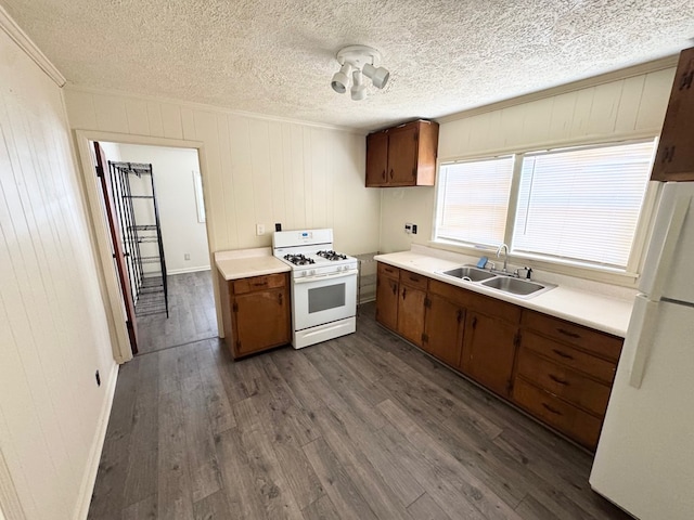 kitchen with sink, white appliances, dark hardwood / wood-style floors, ornamental molding, and a textured ceiling