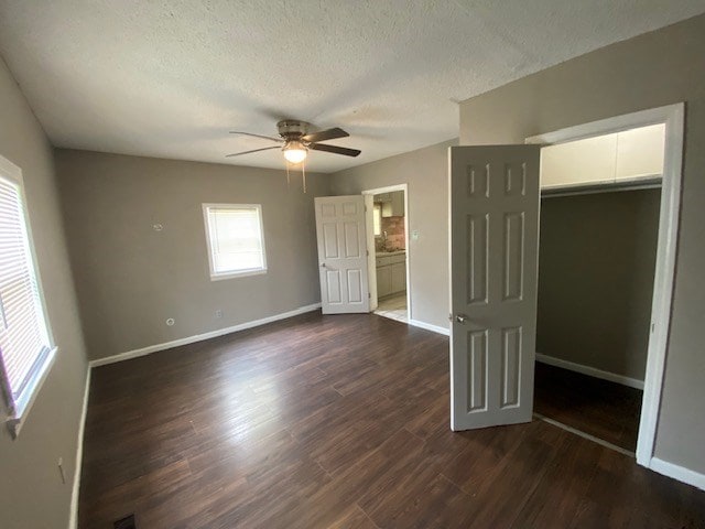 unfurnished bedroom with a closet, a textured ceiling, baseboards, and dark wood-style flooring