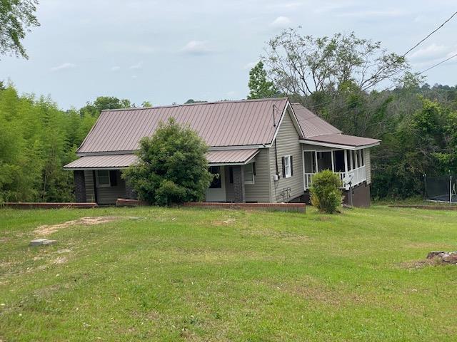 view of front of house featuring a front yard, a sunroom, and metal roof