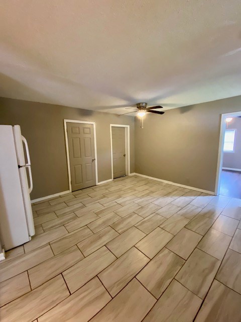 unfurnished room with wood finish floors, baseboards, and a ceiling fan