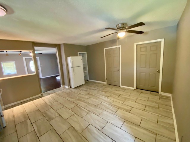 unfurnished room with ceiling fan and baseboards