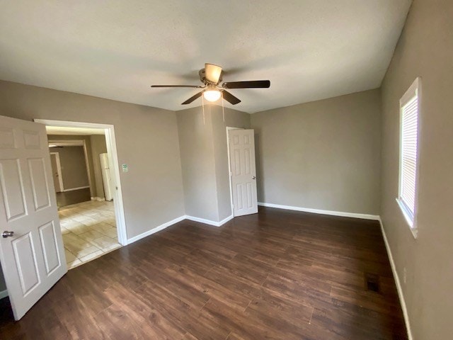 unfurnished bedroom with a ceiling fan, visible vents, wood finished floors, and baseboards