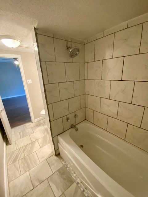 bathroom featuring toilet, a textured ceiling, and bathtub / shower combination