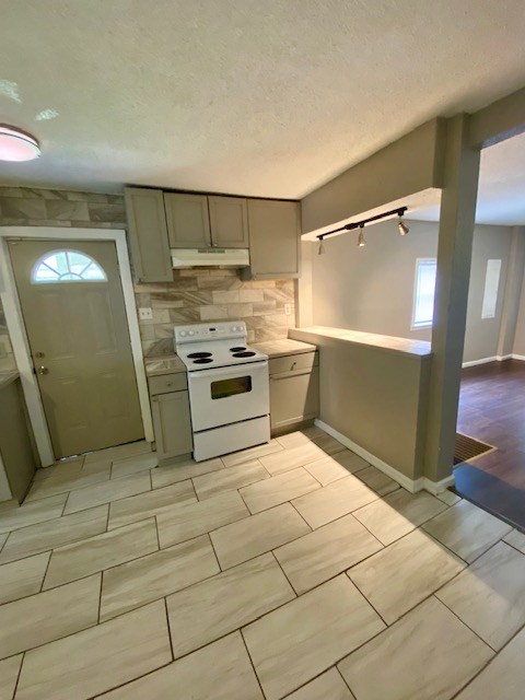 kitchen with gray cabinetry, under cabinet range hood, tasteful backsplash, white electric range oven, and light countertops