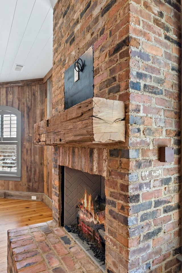 interior details with hardwood / wood-style flooring, a brick fireplace, and wood walls