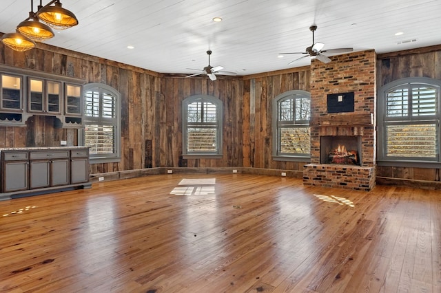 unfurnished living room featuring wood ceiling, ceiling fan, wood-type flooring, and a fireplace