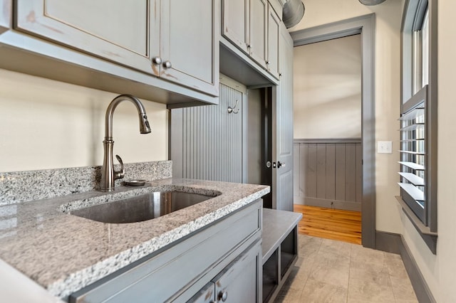 kitchen featuring light stone counters, gray cabinets, and sink