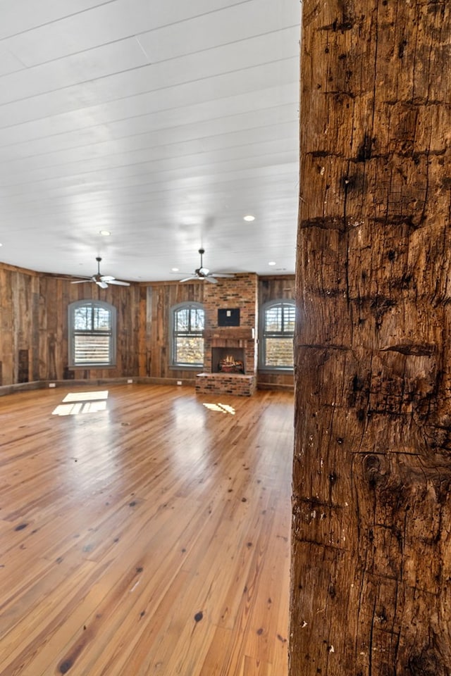 unfurnished living room with ceiling fan, a healthy amount of sunlight, a fireplace, and light hardwood / wood-style flooring