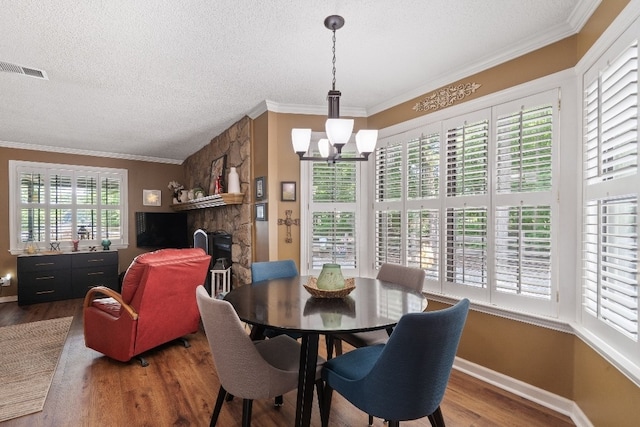 102 E Montego Ct, Milledgeville, GA 31061 - dining space with a chandelier, wood finished floors, a textured ceiling, crown molding, and a fireplace