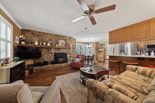 102 E Montego Ct, Milledgeville, GA 31061 - living room featuring crown molding, a textured ceiling, wood finished floors, ceiling fan, and a stone fireplace