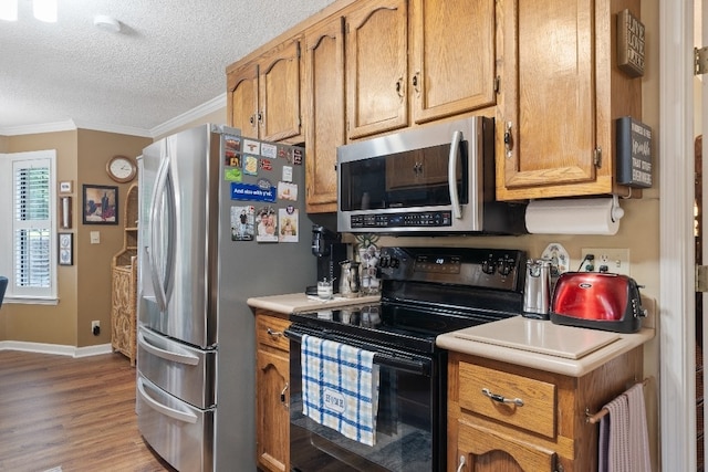 102 E Montego Ct, Milledgeville, GA 31061 - kitchen featuring appliances with stainless steel finishes, crown molding, light countertops, a textured ceiling, and light wood-style floors