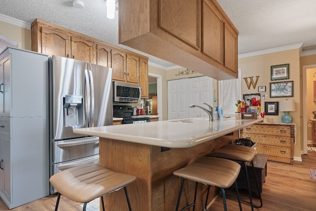 102 E Montego Ct, Milledgeville, GA 31061 - kitchen featuring appliances with stainless steel finishes, ornamental molding, light wood-type flooring, a breakfast bar area, and a textured ceiling