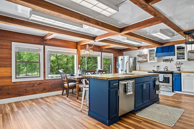 kitchen featuring a kitchen bar, blue cabinetry, white cabinetry, and appliances with stainless steel finishes